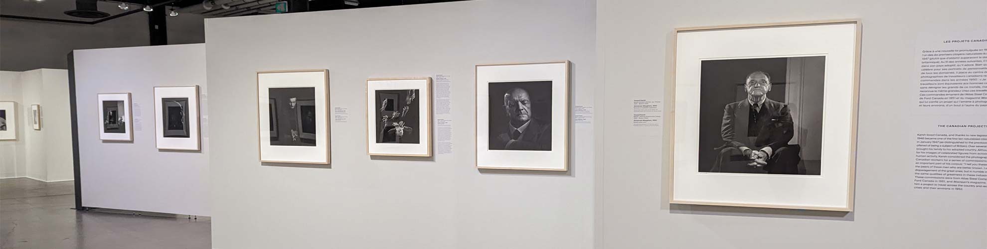 Les photographies sont accrochées à de grands panneaux blancs disposés dans le grand espace. 