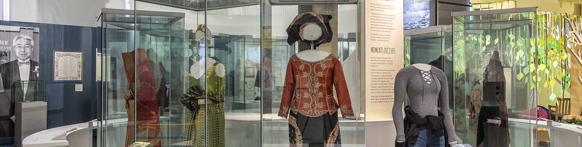 Une image de l’exposition présentant des mannequins avec différents vêtements dans une grande vitrine.