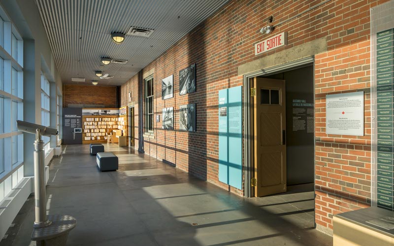 Une salle longue et étroite dont les fenêtres, du sol au plafond à gauche, donnent sur le port. Un mur de briques sur lequel se trouvent deux portes, des photos historiques et deux bancs où les visiteurs peuvent s’asseoir.