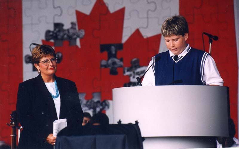 Une femme est sur scène et un jeune homme est sur le podium.
