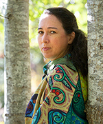 Portrait de l’artiste shalan joudry appuyée sur un arbre, le regard tourné vers la caméra.