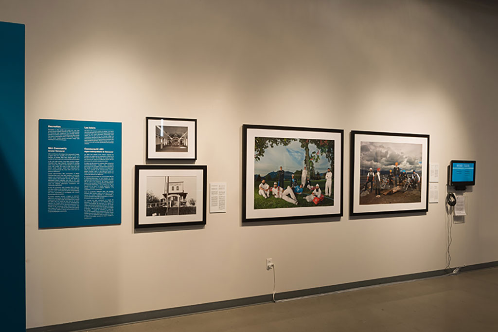 Un long mur avec plusieurs portraits encadrés et des plaques turquoises de texte.