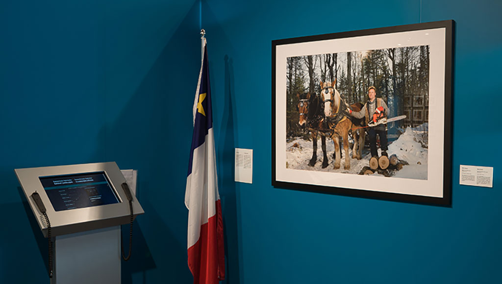 Un grand portrait, accroché au mur, d’un homme dans la neige avec des chevaux de trait et une tronçonneuse.