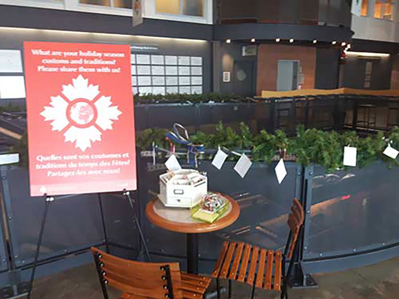 Deux chaises et une table ronde à proximité de l’affiche du logo du Musée canadien de l’immigration du Quai 21.