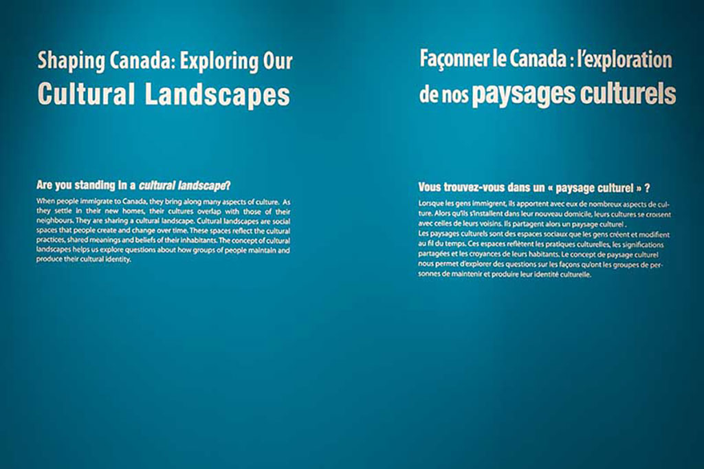 Mur bleu avec du texte en blanc dans le cadre de l’exposition sur les Paysages culturels.