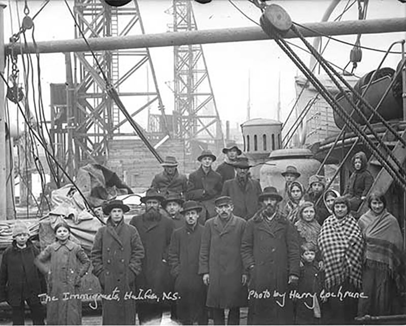 A group of men, women and some children are gathered in the deck of a boat.