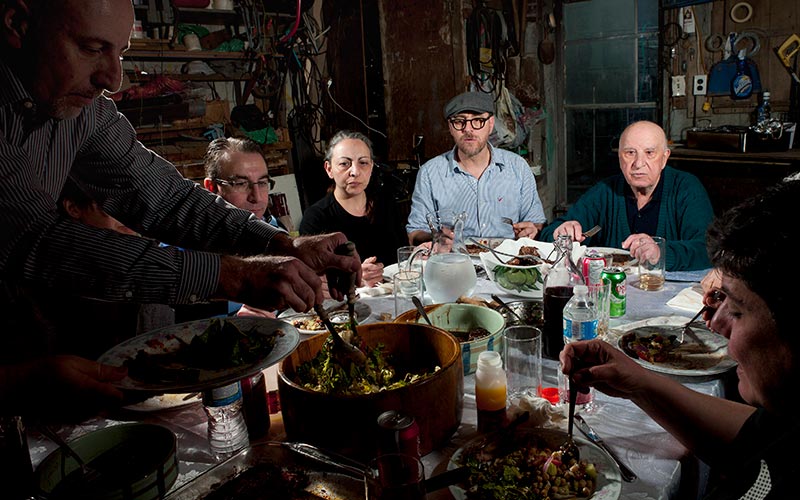 Une famille autour d’une table, avec une personne qui sert de la nourriture dans une assiette.