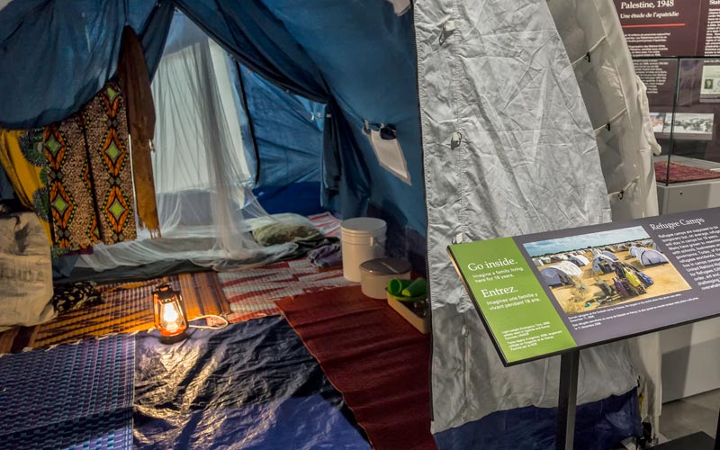 Une tente utilisée dans les camps de réfugiés, avec un panneau d’exposition qui dit « Entrez »