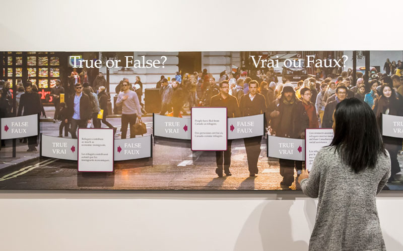 Une personne se trouve devant un panneau d’exposition qui dit « Vrai ou faux? »