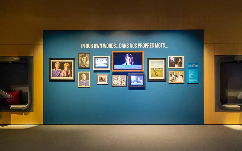 Sur le mur de l'entrée, il y a des photographies et un écran sur lequel est diffusée une histoire orale.