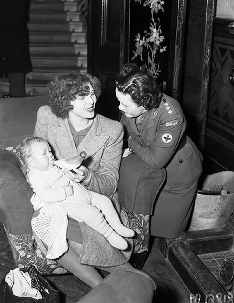 Une femme en uniforme aide une mère et un bébé.