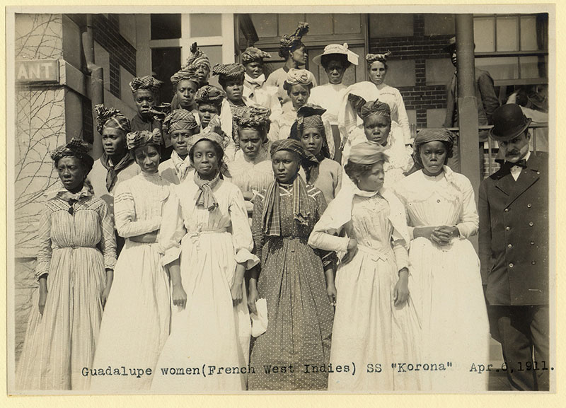 Vingt-deux femmes en robes et un homme en complet regardent la caméra.