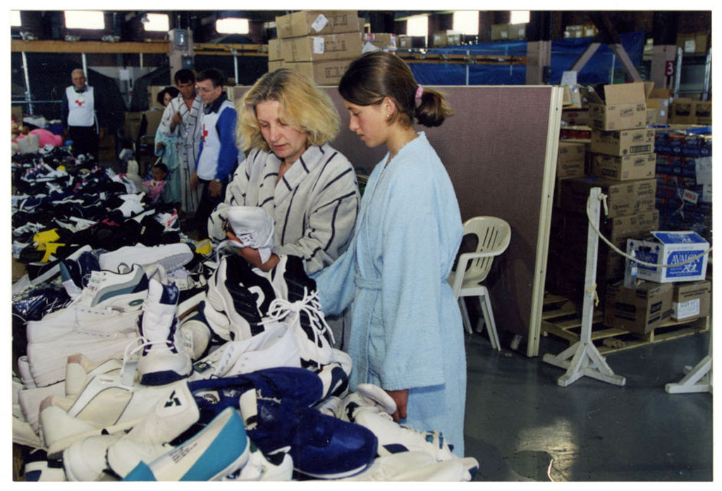 Deux femmes regardant des chaussures empilées sur une longue table.