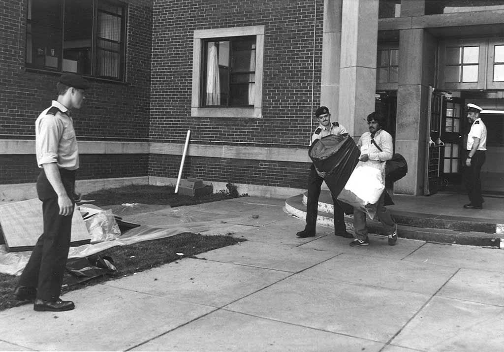 Un jeune homme en uniforme militaire aide un autre homme à transporter ses bagages.