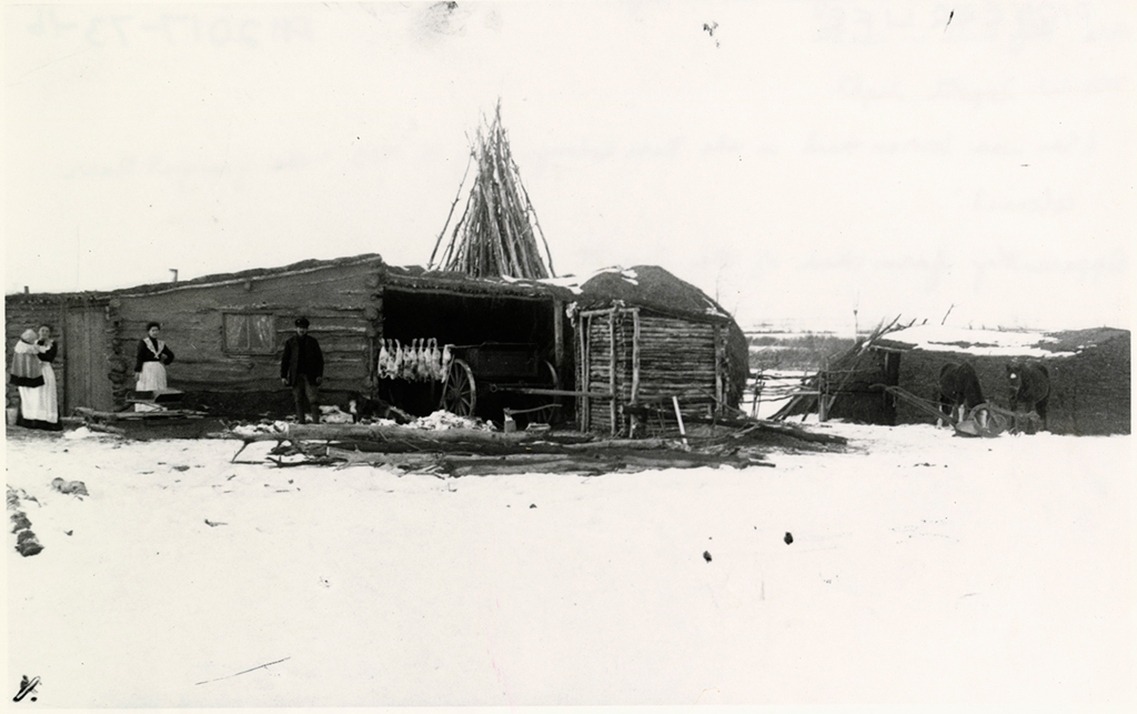 Une vieille ferme avec des gens habillés pour l’hiver.