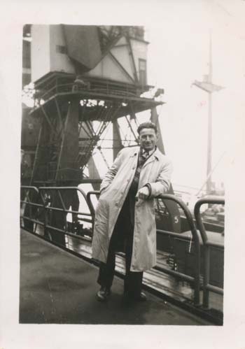Ben en imperméable blanc, appuyé sur la balustrade au quai.