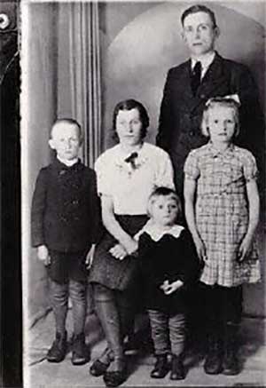 Les membres d’une jeune famille assis pour prendre leur portrait. Leurs expressions sont très sérieuses.