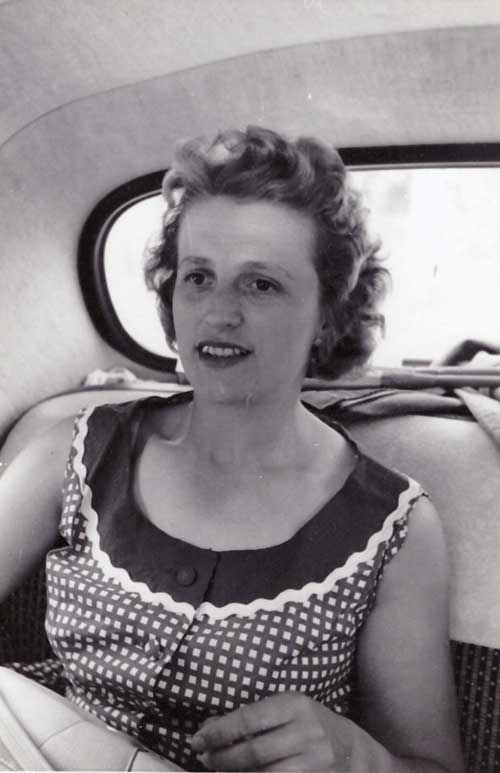 Une jeune femme portant une robe sans manches assise sur la banquette arrière d’une voiture.