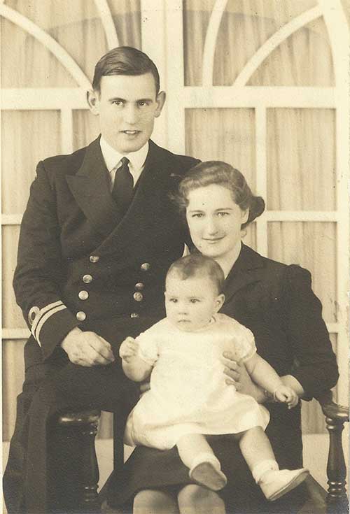 Une jeune femme est assise sur une chaise avec un bébé sur ses genoux et un jeune homme assis sur le fauteuil.