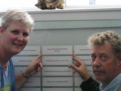 Homme et femme montrant une plaque sur le mur d’honneur du Quai 21.