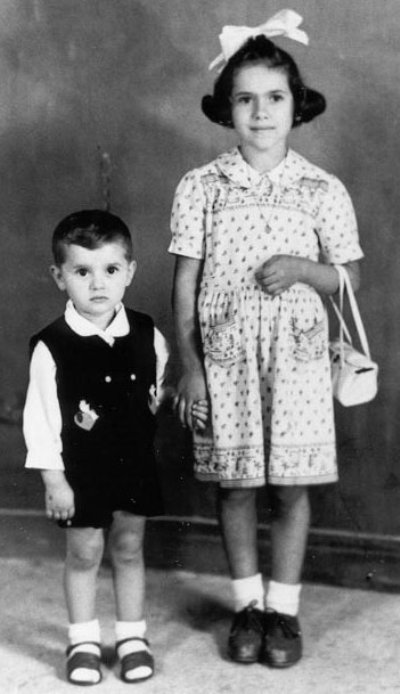 Jeune Luigi et sœur, sœur a grand ruban dans les cheveux et tient un sac à main blanc.