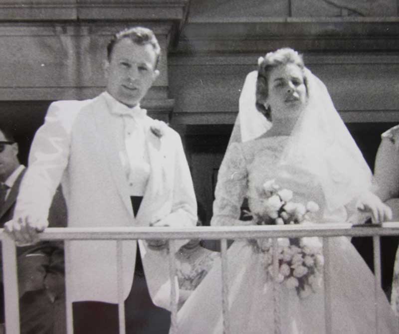 Des mariés à un balcon, le jour de leur mariage.