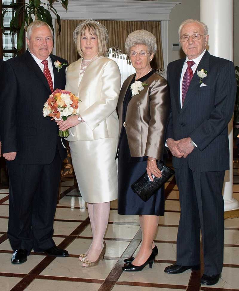 Quatre adultes portant de belles tenues de soirée. Ils se tiennent ensemble et posent pour la photo.