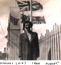 Jeune Norma, debout devant des bâtiments avec des drapeaux britanniques en arrière-plan.