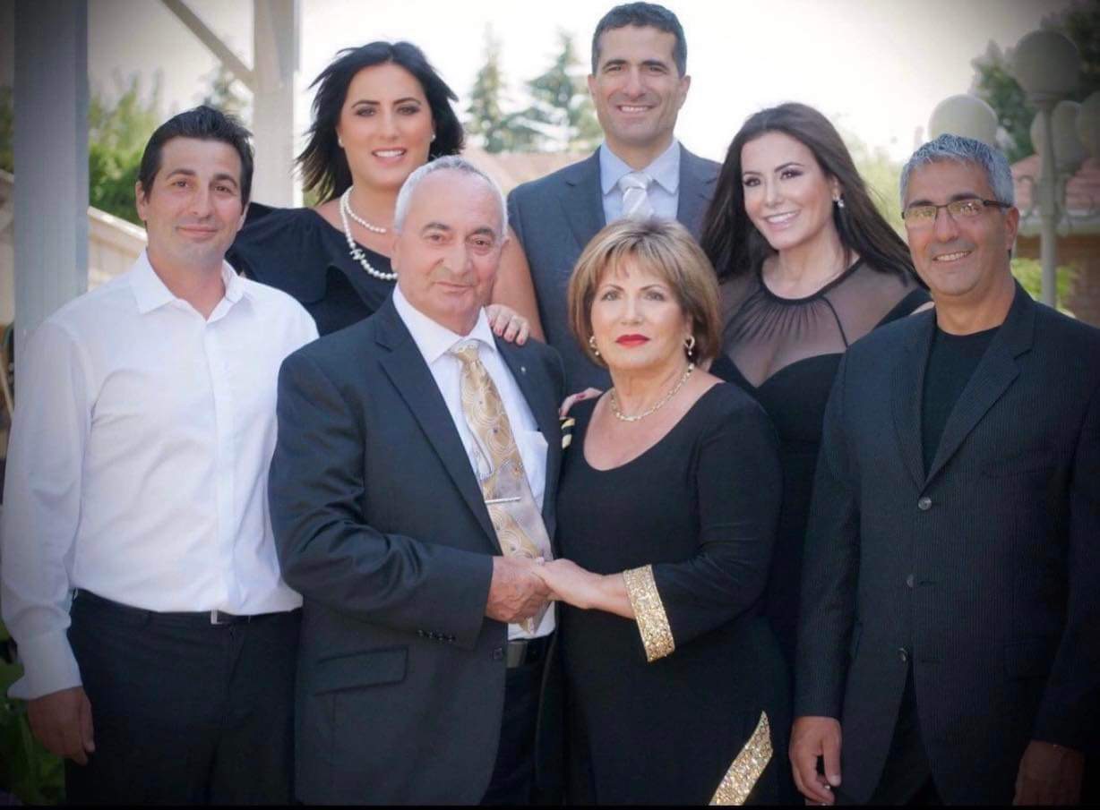 Un portrait de famille avec sept personnes souriantes.