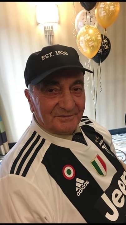 Un homme souriant avec des ballons derrière lui.