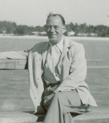 Arthur d’âge moyen assis sur un banc avec de l’eau en arrière-plan.