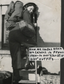 Jeune femme avec un sac à dos, grimpant une échelle et regardant l’appareil photo par-dessus son épaule.