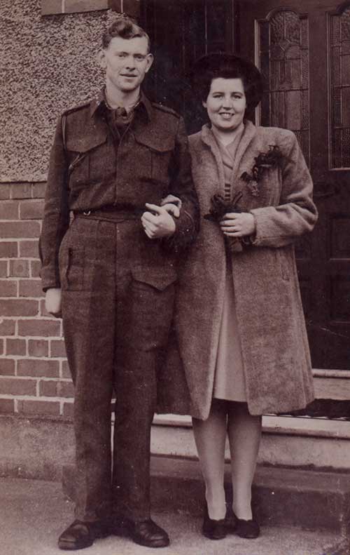 Un jeune homme et une jeune femme se tiennent devant un immeuble.